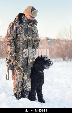 Black grand basset griffon vendéen chien avec son maître sur un marche sur neige hiver Banque D'Images