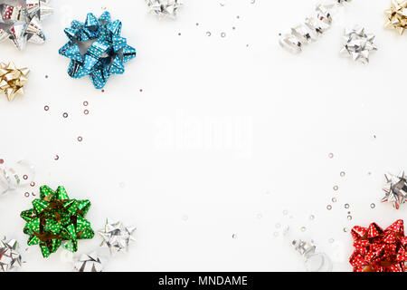 L'emballage de cadeaux colorés des arcs et des paillettes d'argent blanc sur fond de fête. Copie de l'espace. Tirez bow & ruban, vue d'en haut. Banque D'Images