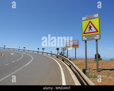 Sentier sur un brusque virage d'une route côtière dans le nord de La Gomera Canaries avec panneau d'avertissement pour les piétons claire Banque D'Images