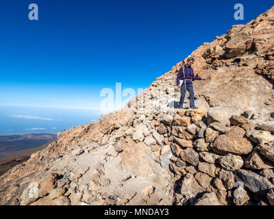 Femme walker descendant du sommet du cratère fumant volcan actif le Mont Teide à 3718 mètres sur Tenerife la plus grande des îles Canaries Banque D'Images