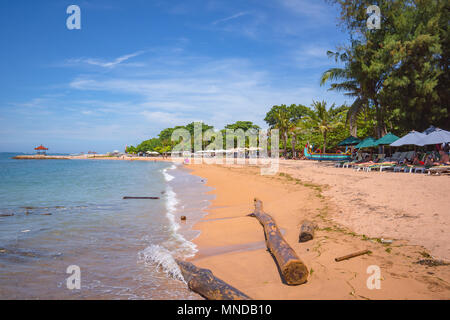 Plage avec chaises longues et deux grosses billes de bois dans l'eau, Sanur, Bali, Indonésie, 21 avril, 2018 Banque D'Images