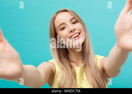 Close-up portrait of attractive young woman stretching her arms, veut vous embrasser. Isolé sur fond bleu. Banque D'Images