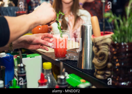 Animateur Expert pro fait mains et de décoration verre cocktail frais rosmarine avec sur le fond de couleur avec les gens. Boire des cocktails, nightlif Banque D'Images