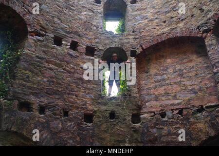 Jeune homme posant jusqu'Glassaugh Moulin Tasse et soucoupe. Moulin à vent en ruine du 17ème siècle. Sandend, Ecosse, Royaume-Uni. Mai, 2018. Banque D'Images