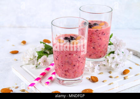 Des smoothies de fruits des bleuets, bananes et amandes dans des verres à cocktail avec tubes sur une planche de bois blanc Banque D'Images