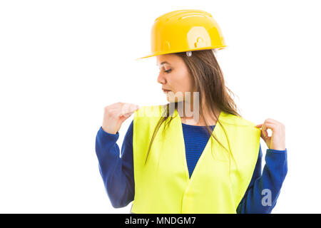 Jeune femme ingénieur ou architecte ajustant son gilet avec les mains aussi se préparer pour le travail concept isolé sur fond blanc Banque D'Images