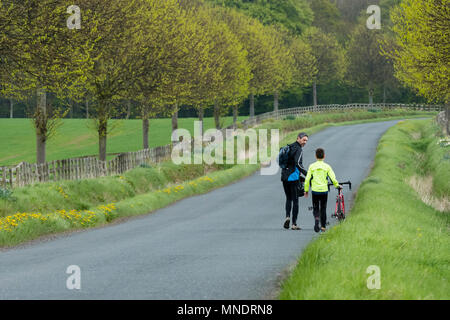 Fatigué après une longue balade en vélo, père & fils sont à pied et en poussant leurs vélos le long chemin de campagne pittoresque - près de Ilkley, North Yorkshire, Angleterre, Royaume-Uni. Banque D'Images