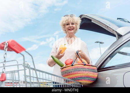 Cheerful senior femme tenant un panier plein de légumes frais Banque D'Images