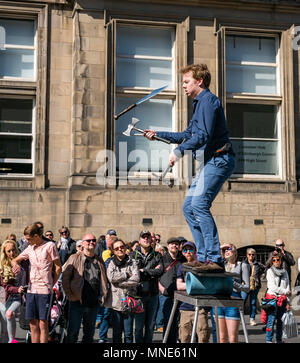 Royal Mile, Édimbourg, 16 Mai 2018. Les touristes profitent du soleil et des divertissements dans la rue sur le Royal Mile, Edimbourg, Ecosse, Royaume-Uni. Les touristes regardent un artiste de rue appelé Daniel, dont l'acte comprend jongler avec des torches flamboyantes et de grands couteaux et machettes Banque D'Images