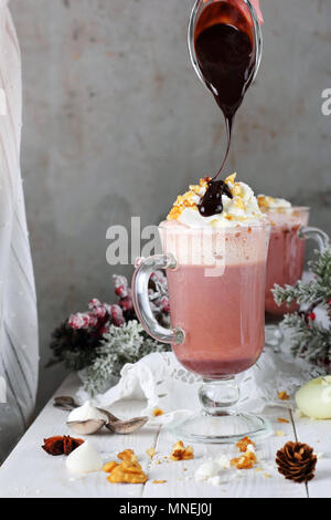 Chocolat chaud avec de la crème fouettée et les écrous versé dans une sauce au chocolat, des décorations de Noël Banque D'Images