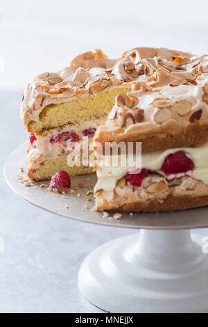 Gâteau rapide à base de génoise, de crème et de framboises avec une garniture à la meringue sur un cake stand Banque D'Images