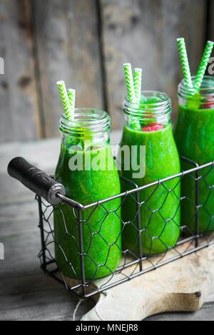 Les smoothies verts et les petites bouteilles en verre garni de framboises Banque D'Images