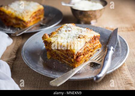 Morceau de lasagne sur une assiette blanche ; Fond blanc Banque D'Images