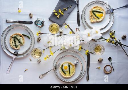 Quiche aux asperges oeuf de caille au plat sur une table à manger pour Pâques Banque D'Images