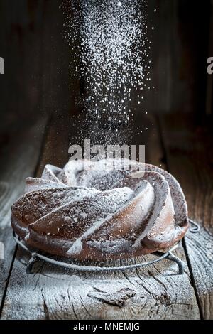 Un gâteau bundt sur une table en bois d'être saupoudrés de sucre glace Banque D'Images