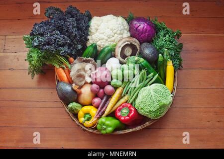 Un panier de légumes sur une surface en bois Banque D'Images