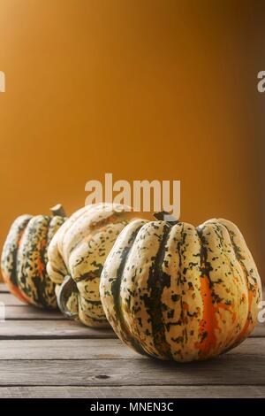 Un arrangement de trois citrouilles contre un fond orange Banque D'Images