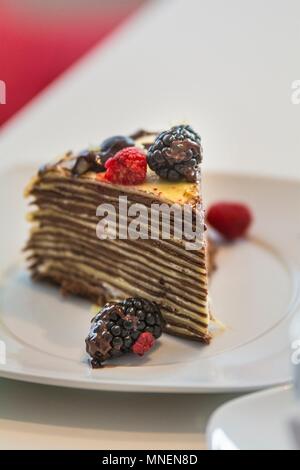 Une tranche de gâteau de crêpes aux fruits rouges et sauce au chocolat Banque D'Images