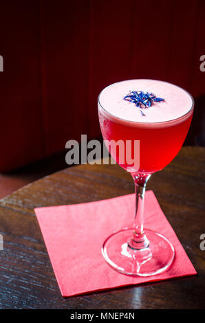 Cocktail rouge décoré de barbeaux sur une serviette de table en bois et rouge Banque D'Images