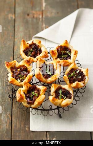 Tartelettes de pâte feuilletée avec tomates séchées, oignons caramélisés et thym Banque D'Images