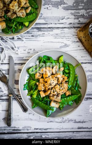 Poulet grillé aux épinards, roquette et petits pois sur la surface en bois rustique Banque D'Images