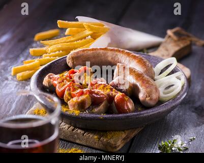 Saucisses au curry avec des frites et oignons Banque D'Images