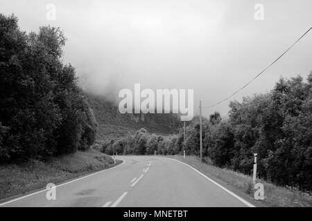 Une route sinueuse à travers les montagnes norvégiennes avec les nuages bas. Banque D'Images