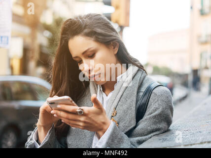 Femme à l'aide de son téléphone portable dans la rue. Banque D'Images