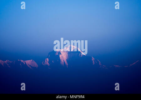 La première lumière du soleil touchant mont Dhaulagiri de l'Annapurna Himalaya dans la gamme ciel brumeux et faible lumière pour l'arrière plan. Banque D'Images