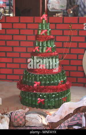 Arbre de Noël à partir de bouteilles Vert Rouge avec guirlandes et arcs rouges, Colva, India Banque D'Images