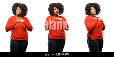 Les jeunes de l'Afrique belle grande taille modèle avoir charmant sourire tenant la main sur le coeur, qui souhaite montrer l'amour et la sympathie isolated over white background. Banque D'Images