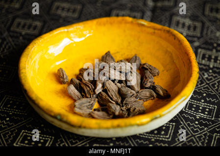 Cardamome noire dans bol jaune Banque D'Images