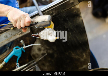 Artiste de verre dans un verre fabrication travaille sur seagull sculpture faite de verre chaud. Se concentrer sur les mains et la figure seagull. Close up shot Banque D'Images