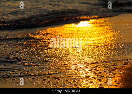 Belles formes colorés créés par les vagues sur une plage de sable et de réflexions soleil au coucher du soleil Banque D'Images