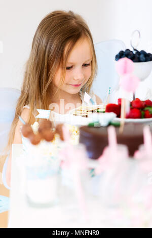 Adorable petite fée fille sur une fête d'en face de la table à dessert Banque D'Images