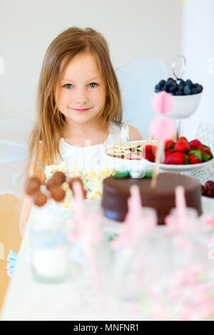 Adorable petite fée fille sur une fête d'en face de la table à dessert Banque D'Images