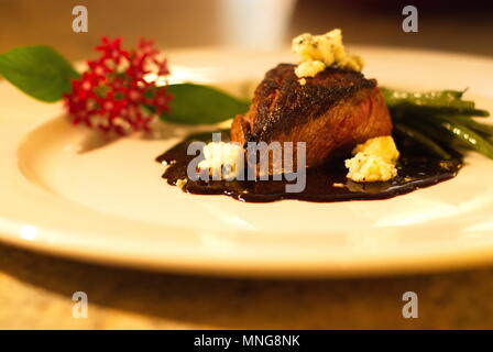 Dîner de boeuf avec sauce au fromage bleu ,, et haricots verts présentés avec décoration florale et offert sur plaque unique de près, sains et nutritifs. Banque D'Images