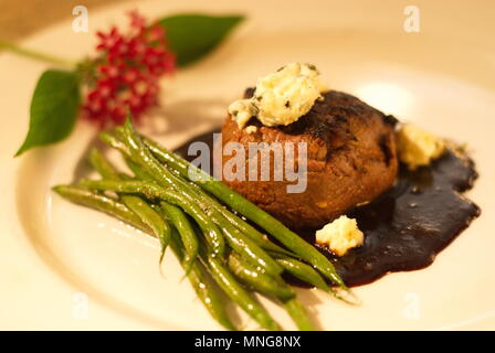 Dîner de boeuf avec sauce au fromage bleu ,, et haricots verts présentés avec décoration florale et offert sur plaque unique de près, sains et nutritifs. Banque D'Images