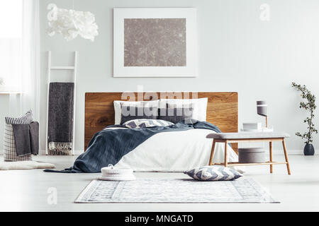 La peinture argentée sur mur blanc au-dessus de lit dans la chambre à coucher design intérieur avec bain, lampes et les draps Banque D'Images