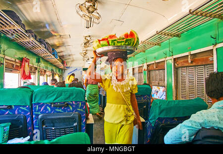 YANGON, MYANMAR - février 16, 2018 : La petite fille vend des tranches de melon d'eau douce, le transporter dans le bac sur sa tête en wagon du train, sur Febr Banque D'Images