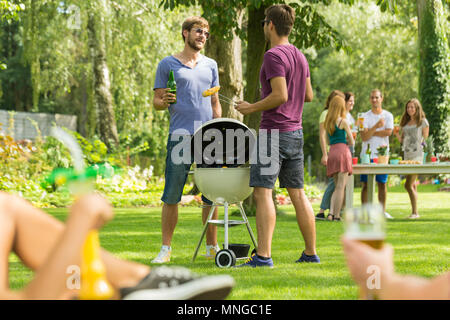 Deux hommes debout à côté du barbecue dans le jardin Banque D'Images