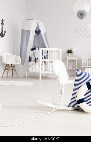 Belle chambre bébé blanc avec lit-bébé et cheval à bascule avec des décorations dans le style de la marine Banque D'Images