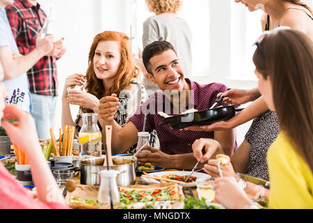 Jeune femme partage bio et repas frais avec son ami pendant le dîner dans la maison Banque D'Images
