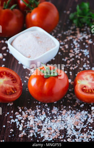 Les tomates biologiques et de sel de roche sur un fond de bois Banque D'Images