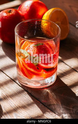 Orange sanguine rafraîchissante de l'eau ou de l'eau infusée dans un verre sur un fond de bois. Banque D'Images