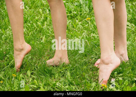 Jambes élancées de deux filles marche pieds nus sur l'herbe de près. Banque D'Images