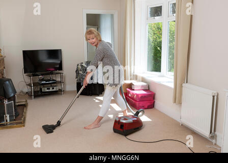 Déménagement, femme à l'aide d'un aspirateur pour aspirateur très hoover le tapis avant de déménager hors de la propriété. Banque D'Images