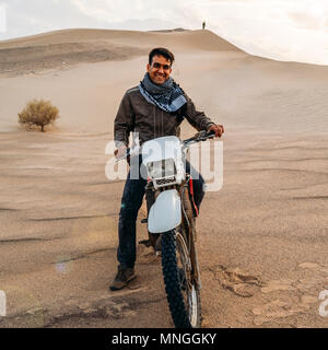 Dasht-e-Lut, l'Iran - 25 Avril 2018 : rédaction d'illustration d'un jeune homme sur une moto posant à Dasht-e-Lut, un grand désert de sel situé dans le pr Banque D'Images