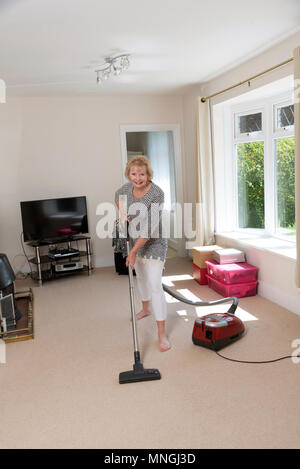 Déménagement, femme à l'aide d'un aspirateur pour aspirateur très hoover le tapis avant de déménager hors de la propriété. Banque D'Images