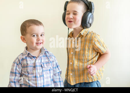 Un petit garçon avec ses écouteurs danse avec son frère. Deux petits frères en shirts s'amuser et danser. Deux frères s'amusent. Banque D'Images